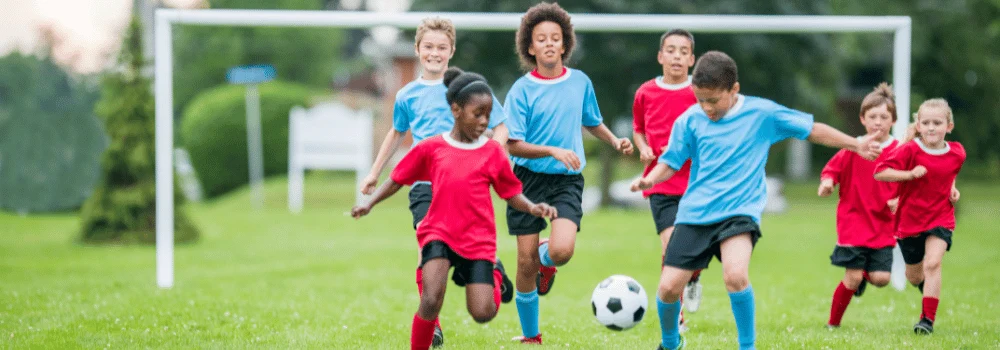 Flickor och pojkar i två lag som spelar fotboll