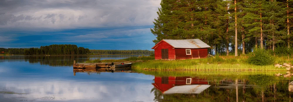 Rött timmrat hus så kallat häbre vid en vacker sjö i Sveriges inland 