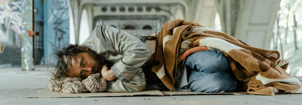 Hemlös man som sover under en bro på en bit kartong